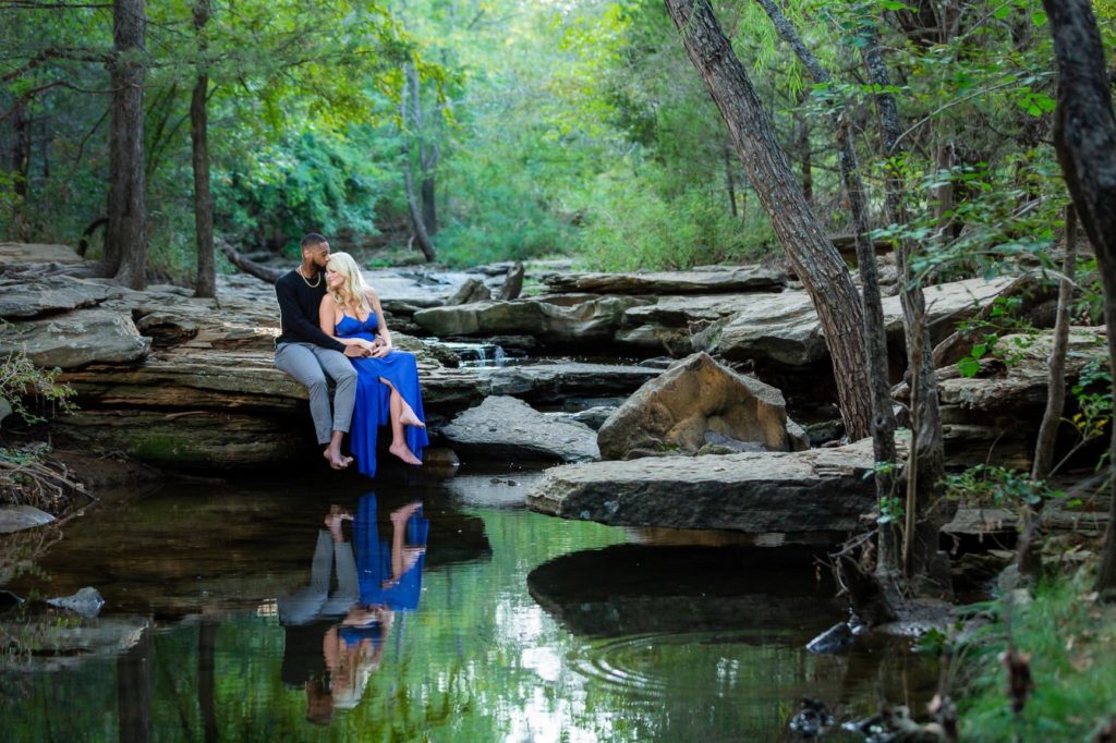 Engaged couple sitting on rocks at stone creek park in flower mound