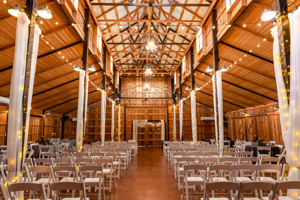 reception hall at the Big White Barn Dallas wedding venue deorated with white drapes, lights and chairs