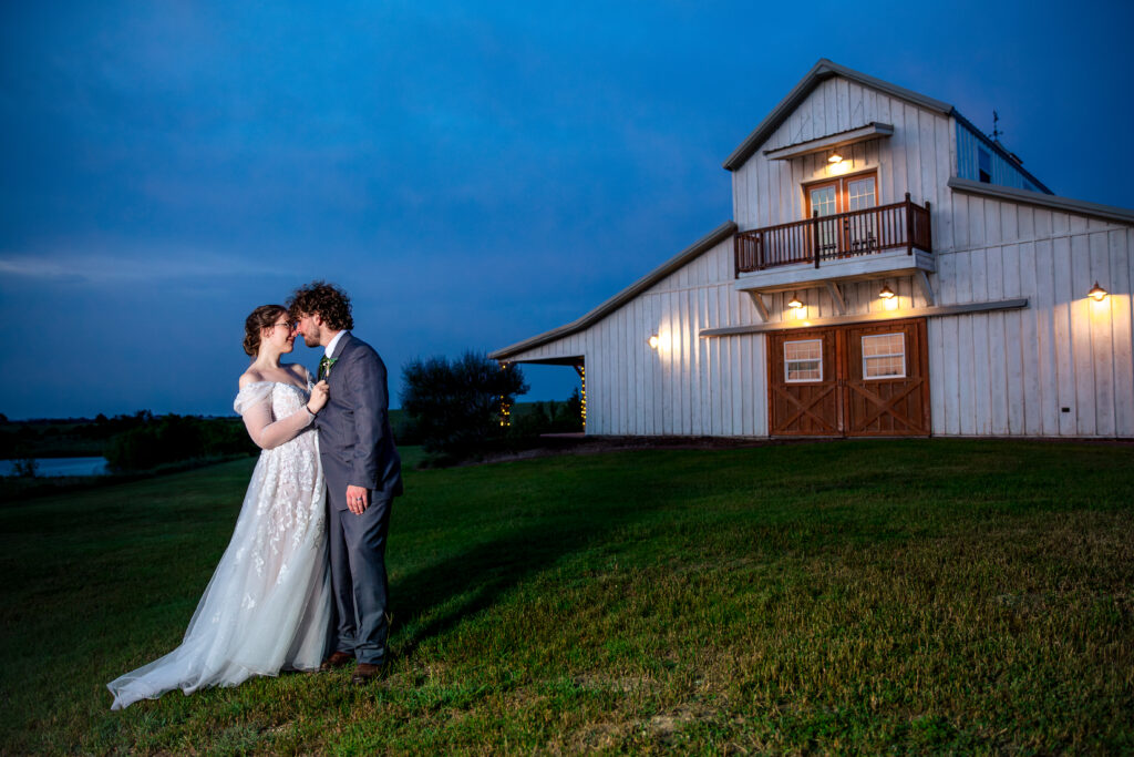 night time weddingpictures by Dallas wedding photographer with bride and groom embracing outside of the big white barn dallas wedding venue