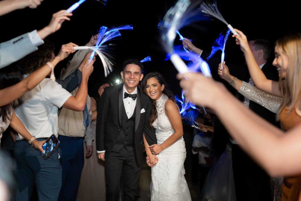 destination wedding with bride and groom holding hands and walking through light wands for their night time wedding send off with Dallas wedding photographers