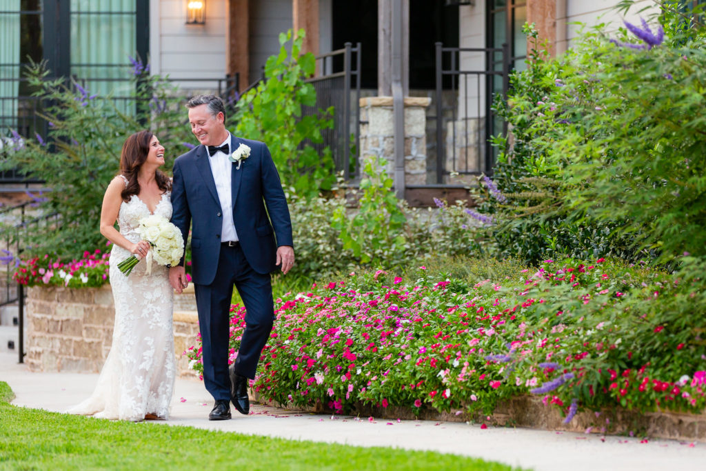 bride and groom holding hands and walking down a path together for their Granbury wedding in Dallas Texas