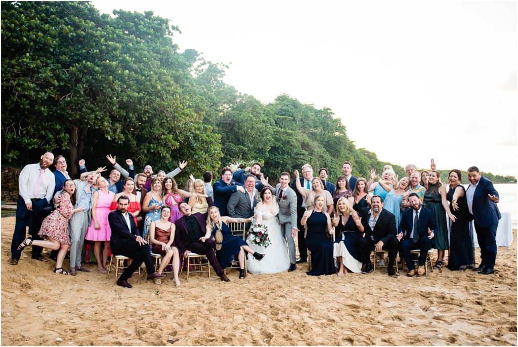 bride and groom with entire wedding party and guests on sand during beach ceremony on Laughing Waters in Jamaica