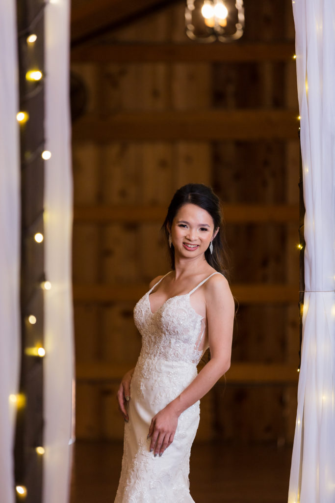 Dallas wedding photographer captures bridal portraits of the bride in front of a simple background of barn doors and twinkle lights