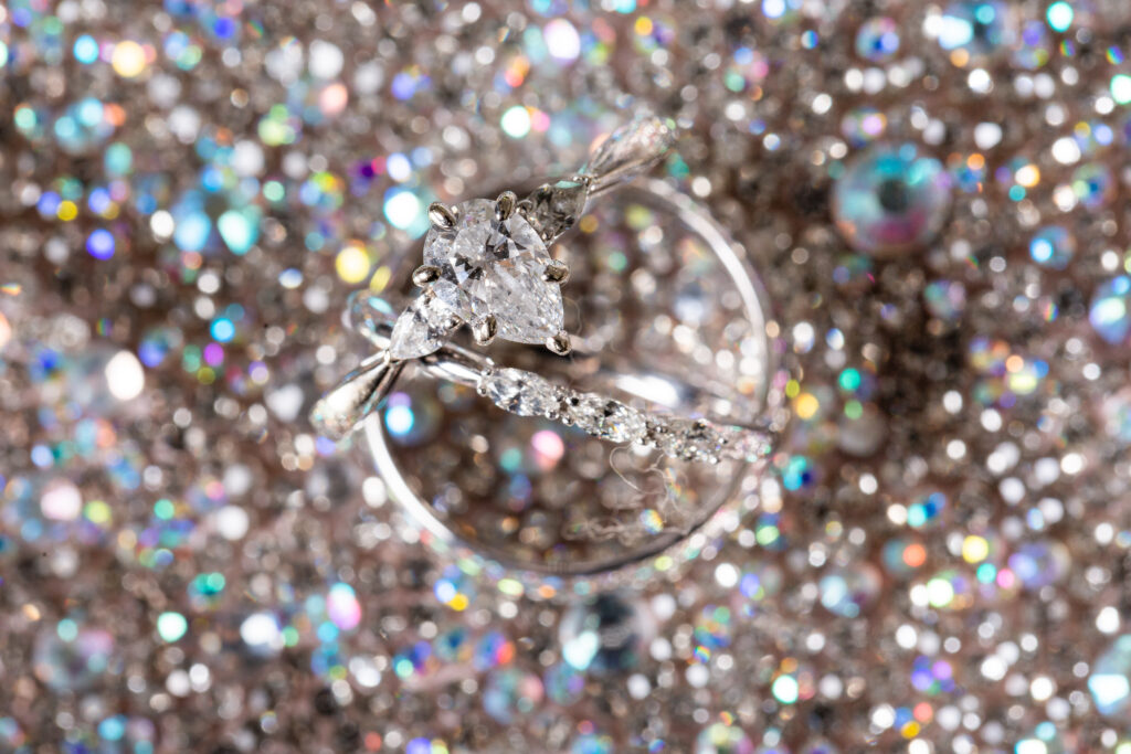 Detail shot by dallas photographer of bride's engagement ring and groom's wedding band on top of a sparkle background