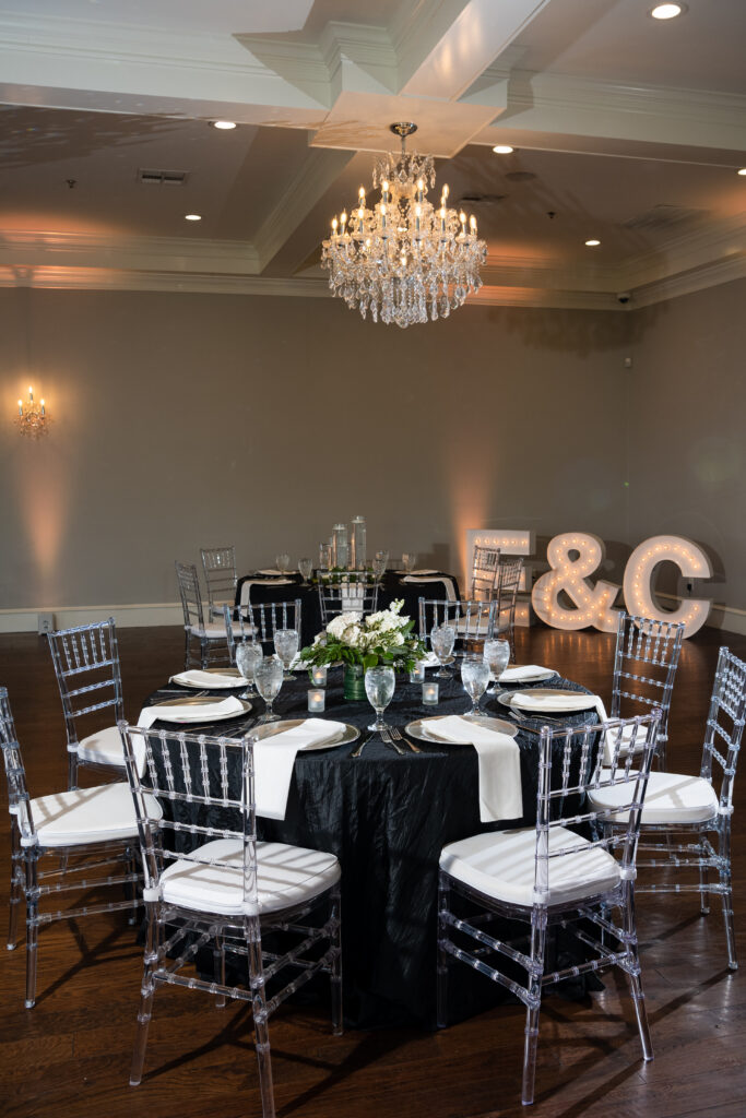 reception space in the milestone denton with tables set up with black table clothes, white chairs and elegant greenery details