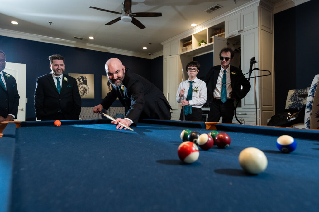 Groom playing pool in grooms suite with wedding party before wedding ceremony at Milestone Denton in Texas by Dallas wedding photographers