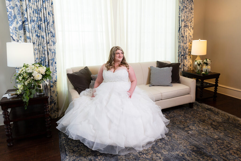 Bride sitting in wedding gown on couch in bridal suite at Milestone wedding venue in Denton TX