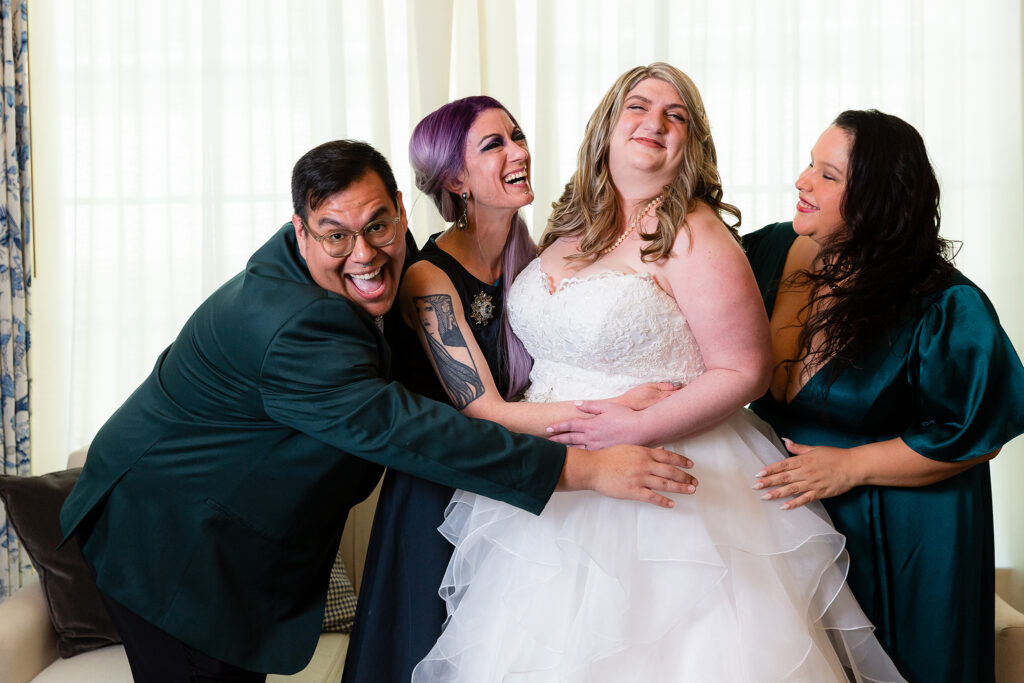 Bride being hugged by bridal party while laughing