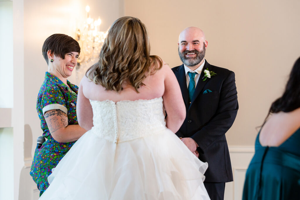 Groom and officiant laughing towards bride during wedding ceremony at milestone denton wedding venue by Stefani Ciotti Photography