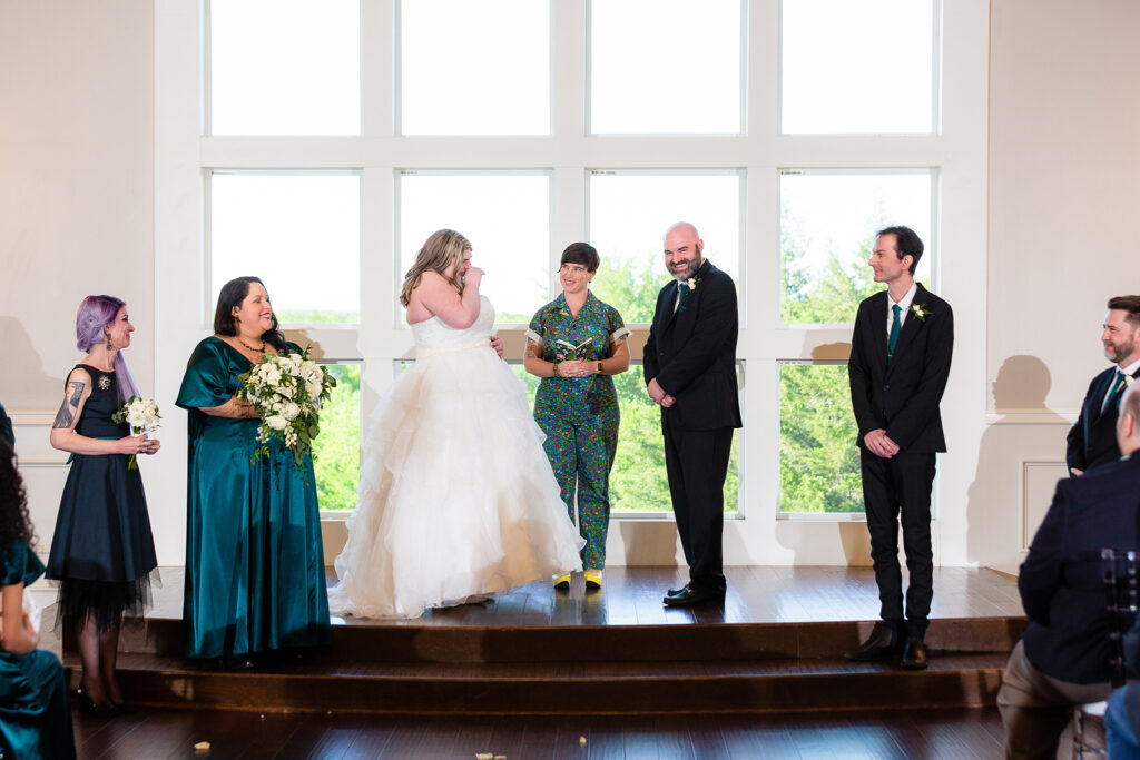 Bride, groom and wedding party laughing during indoor ceremony at milestone denton's chapel