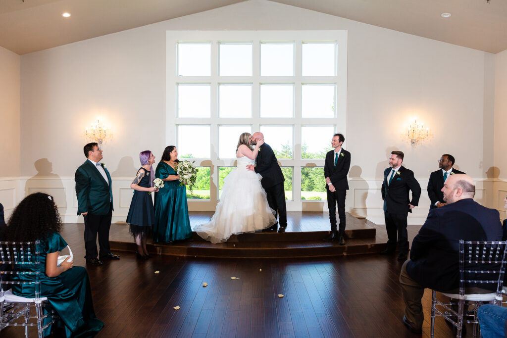 Bride and groom first kiss during wedding ceremony in chapel at milestone denton venue