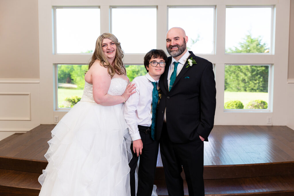 Bride, groom and son smile together after wedding ceremony