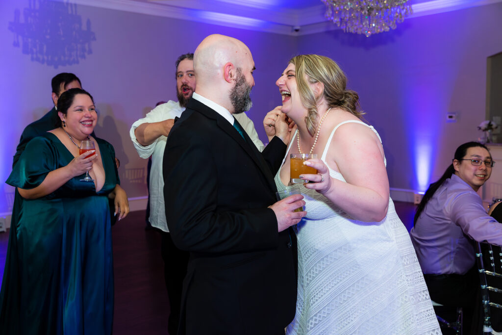 Bride and groom laugh and dance in reception hall at milestone denton venue