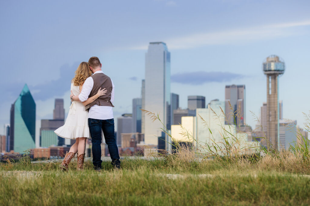 Dallas wedding photographer Stefani Ciotti Photography captures engaged couple hugging and looking out at downtown Dallas skyline