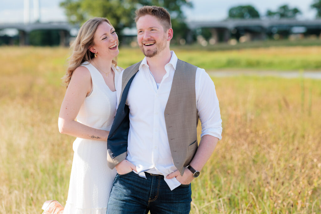 Engaged couple laughs during engagement session at Trinity Overlook Park by Dallas wedding photographer Stefani Ciotti Photography