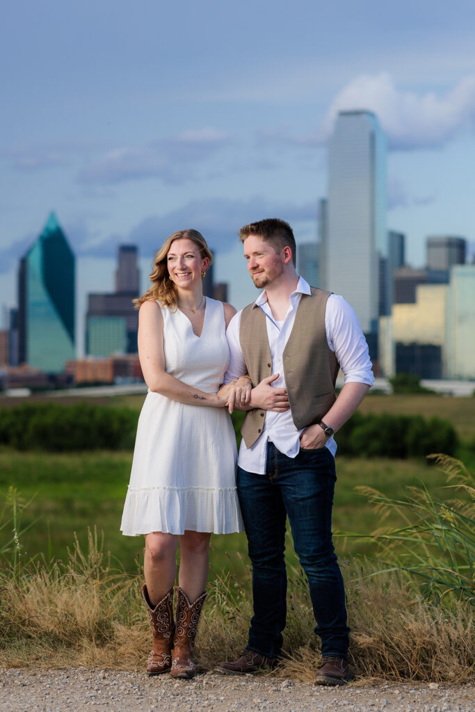 Dallas wedding photographers capture man looking at fiancee while she smiles during outdoor Dallas engagement