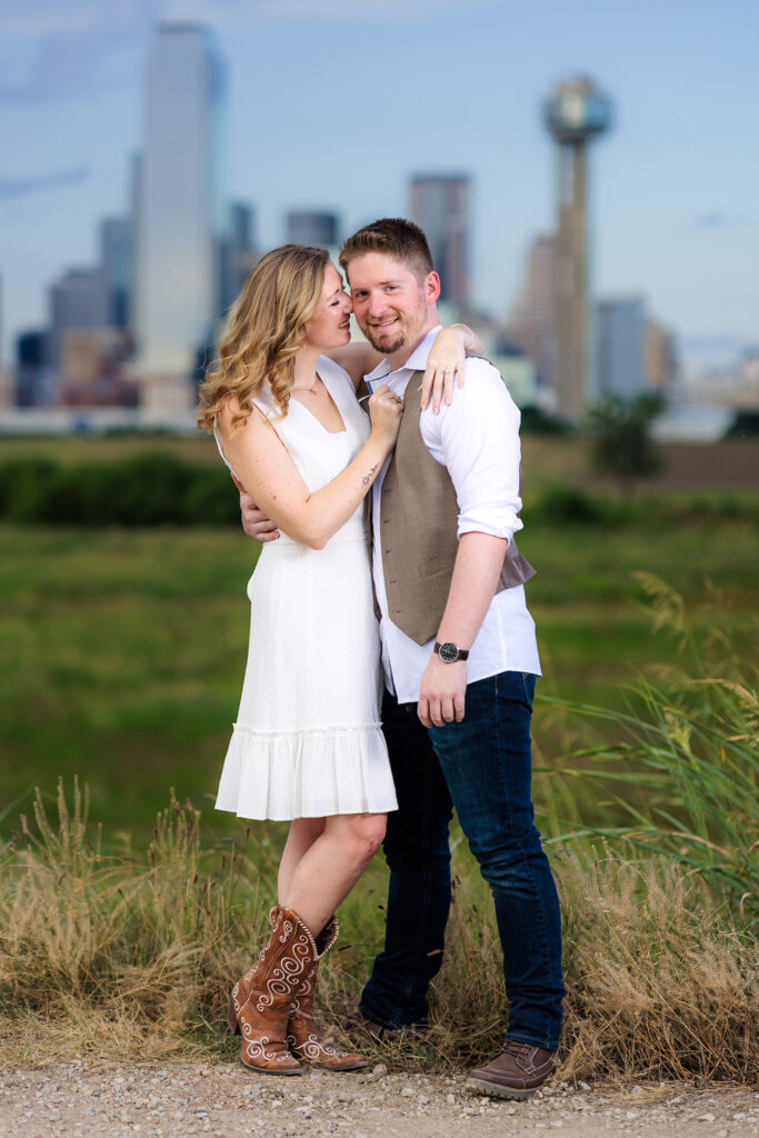 Dallas wedding photographers capture woman looking at fiance during Downtown Dallas skyline engagements
