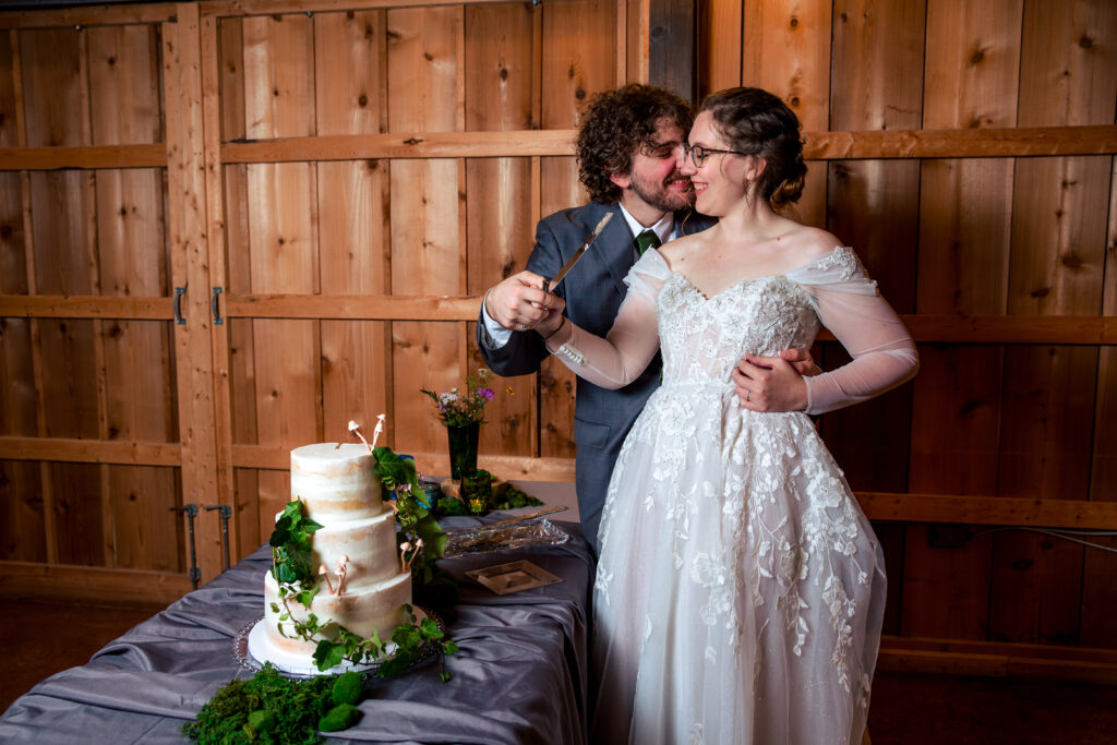 Dallas wedding photographers capture bride and groom hugging before cutting cake