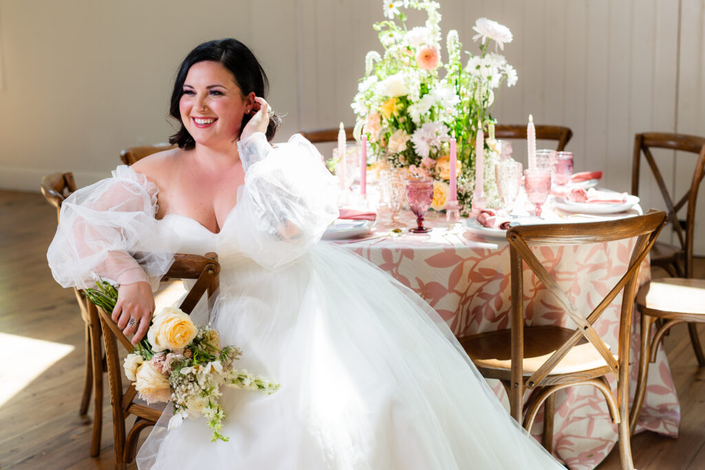 Dallas wedding photographer Stefani Ciotti Photography captures bride sitting on chair, holding bridal bouquet and smiling across room