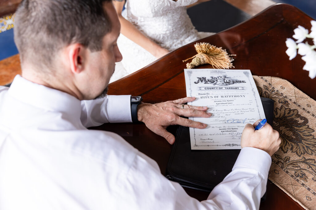 Officiant signing Texas Marriage License on wooden table