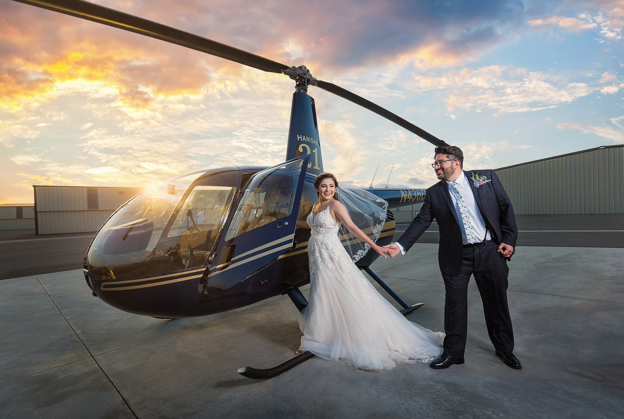 bride walking onto a helicopter on a rooftop with a sunset in the distance while her groom holds her hand captured by Dallas wedding photographers