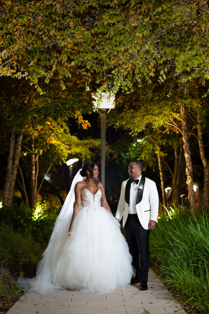 Bride and groom walking through trees on Hotel Crescent Court property photographed by Dallas wedding photographers