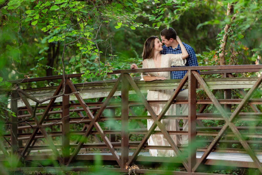 Couple standing on bridge during engagement photo session in Dallas