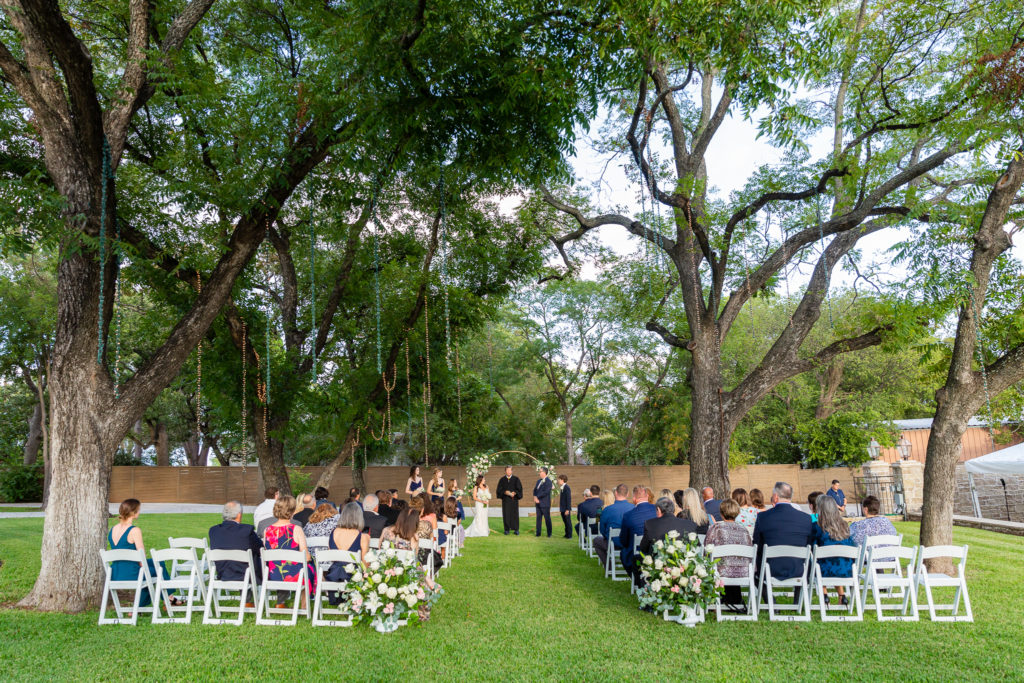 Grassy ceremony site with tall trees at Hotel Lucy in Granbury
