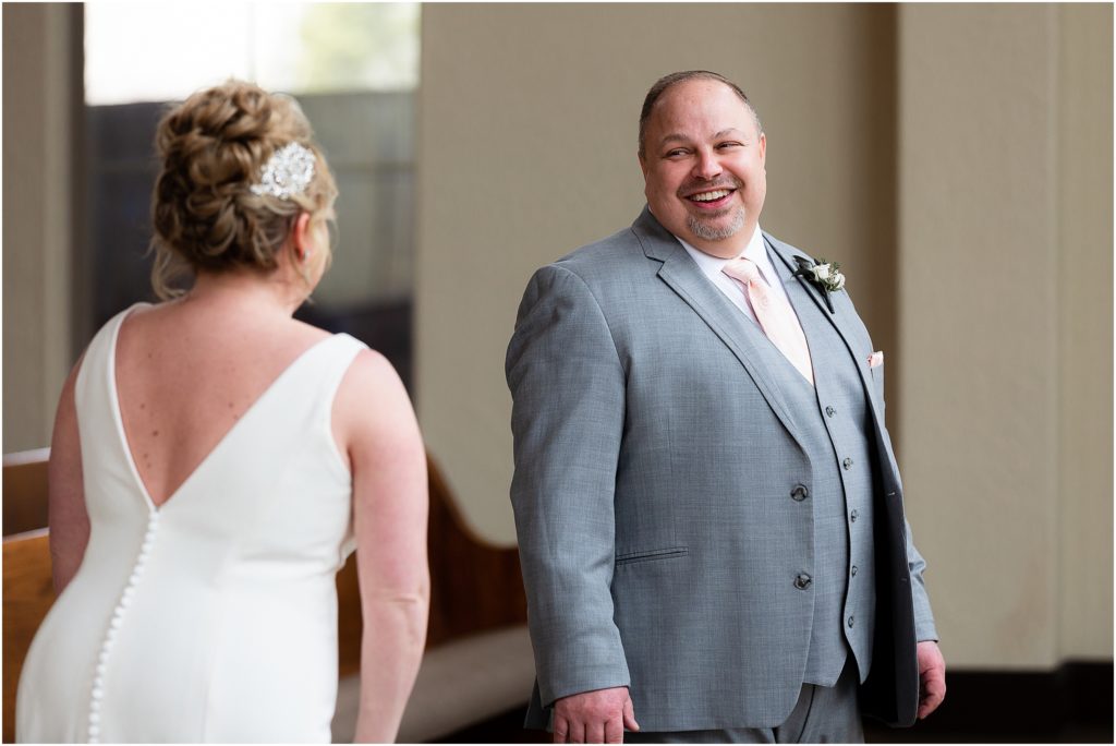 Groom Chris looks at bride lovingly during their first look in Ana Villa wedding venue chapel captured by Dallas wedding photographer