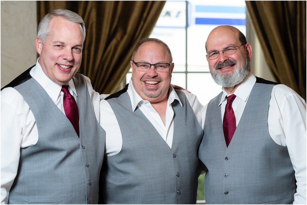 The groom and his groomsmen smile broadly in grey vests captured by Dallas wedding photographers