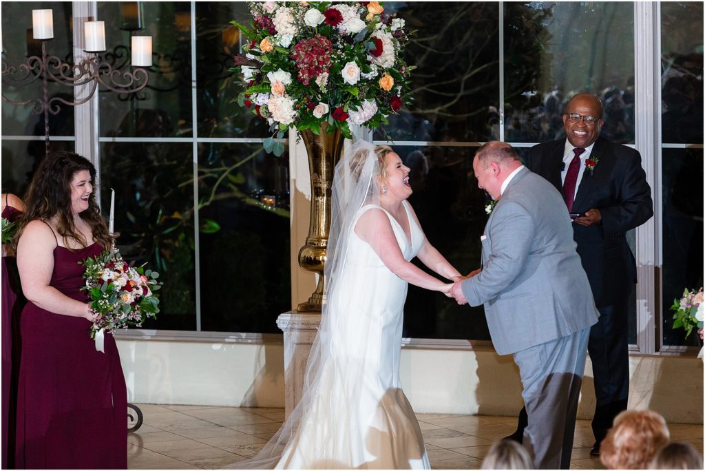 Bride and groom laugh loudly in front of officiant during their Dallas wedding ceremony by Dallas wedding photographers