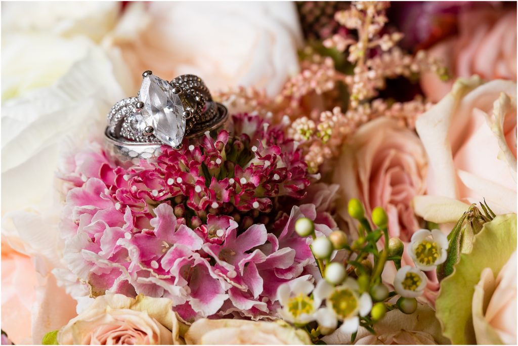 silver oval wedding ring set in pink bouquet flowers captured by Dallas wedding photographers