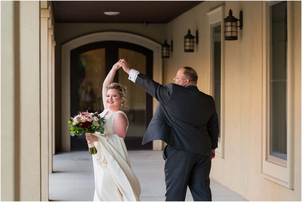 The groom twirls the bride, who holds her bouquet, outside a luxury Dallas wedding venue captured by Dallas wedding photographers