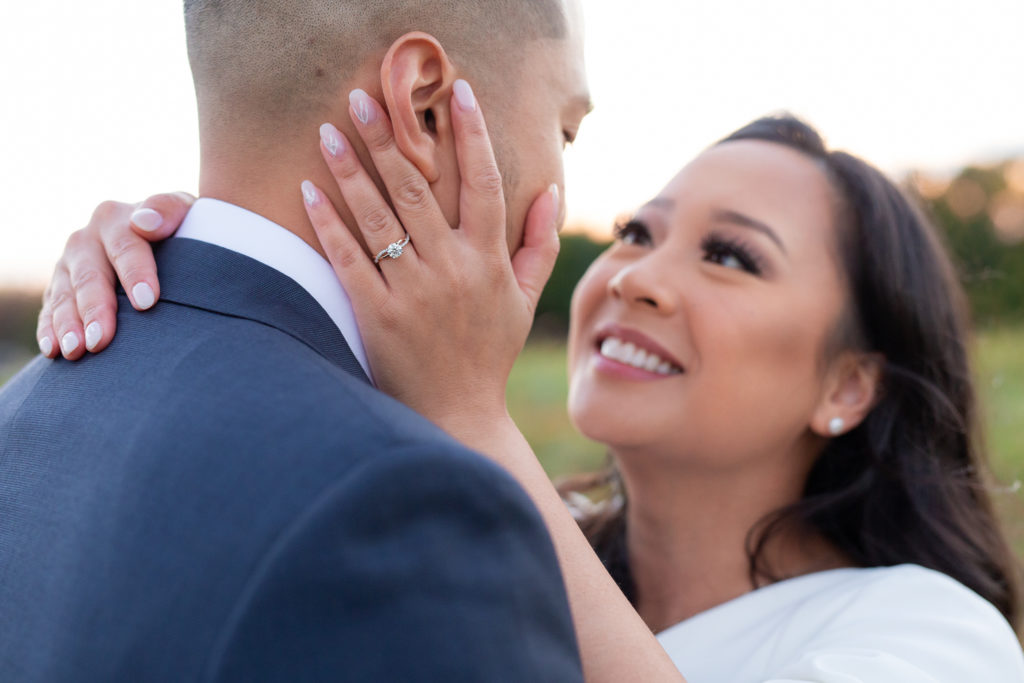 engagement ring shot with woman holding her grooms face for their outdoor engagement session captured by Dallas wedding photographer