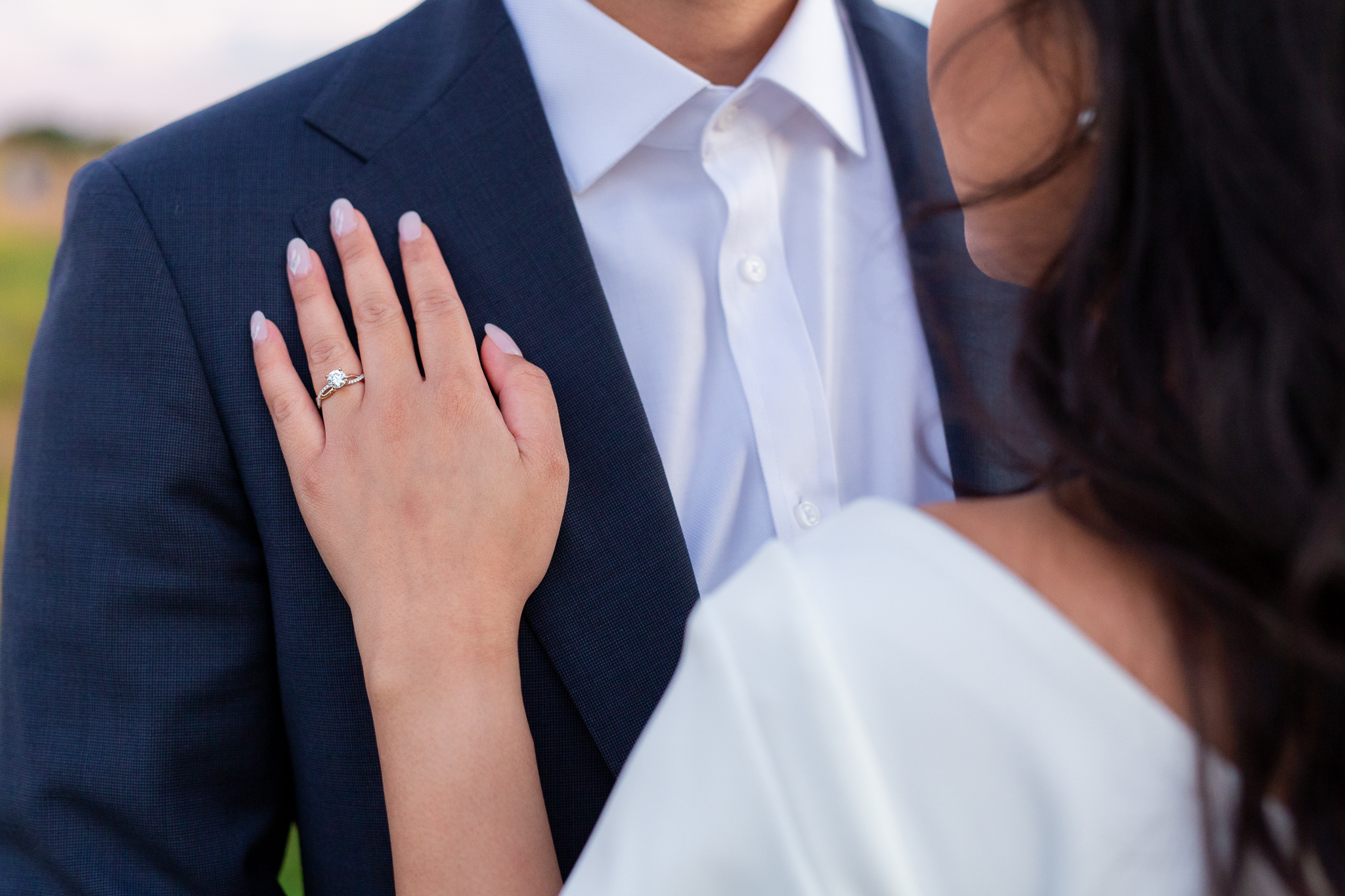 Dallas wedding photographer captures detail shot of engagement ring as the woman holds her hand over the grooms suit coat