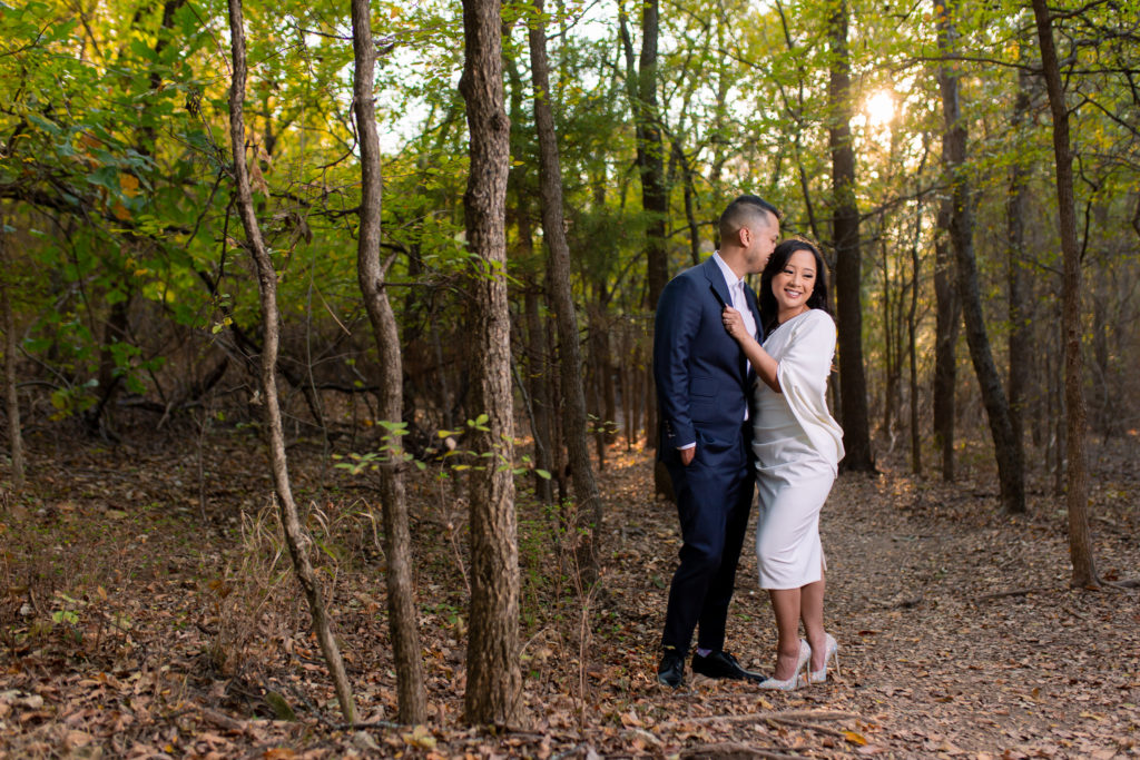 Groom kissing bride in wooded forest