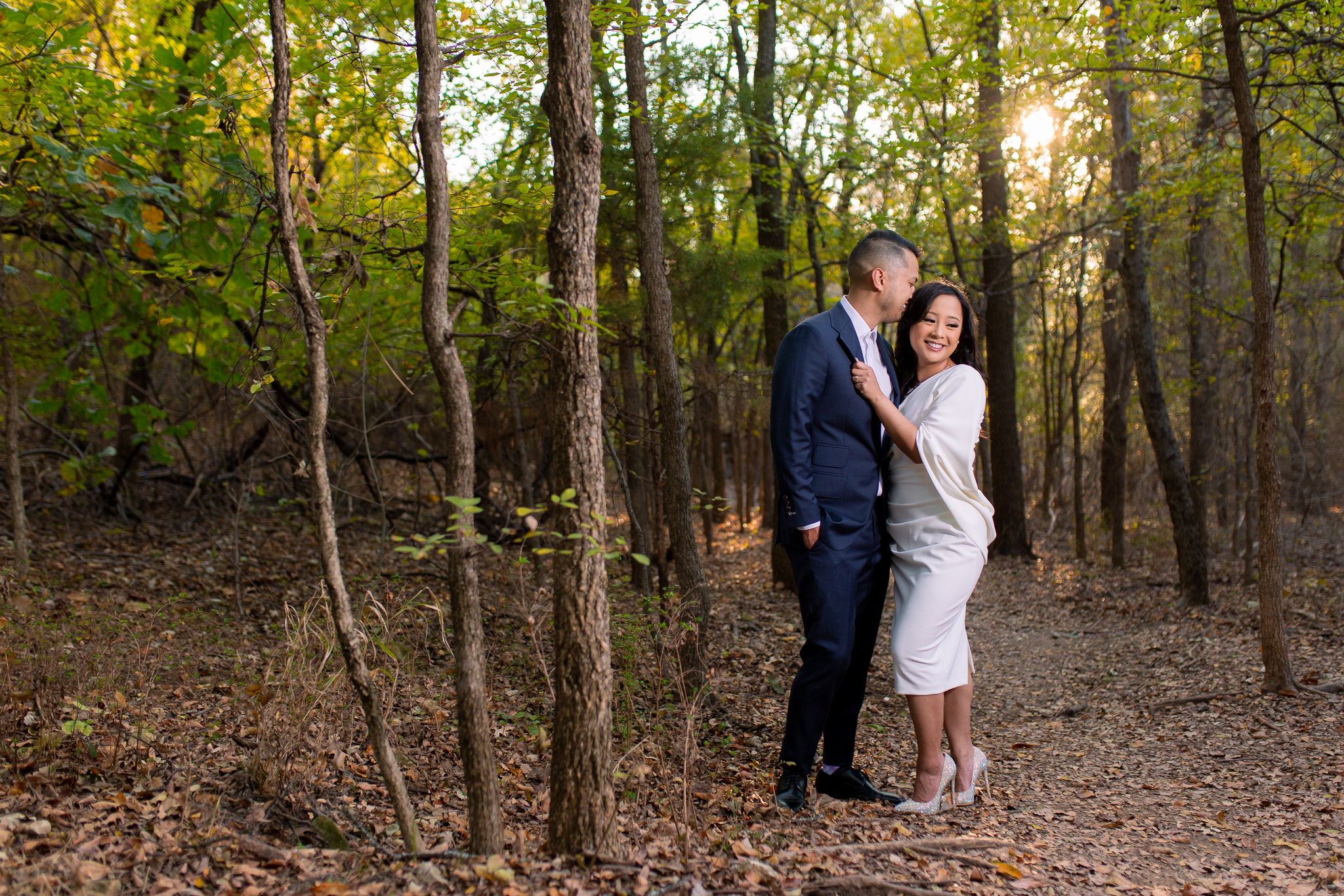 Groom kissing bride in wooded forest in dallas texas