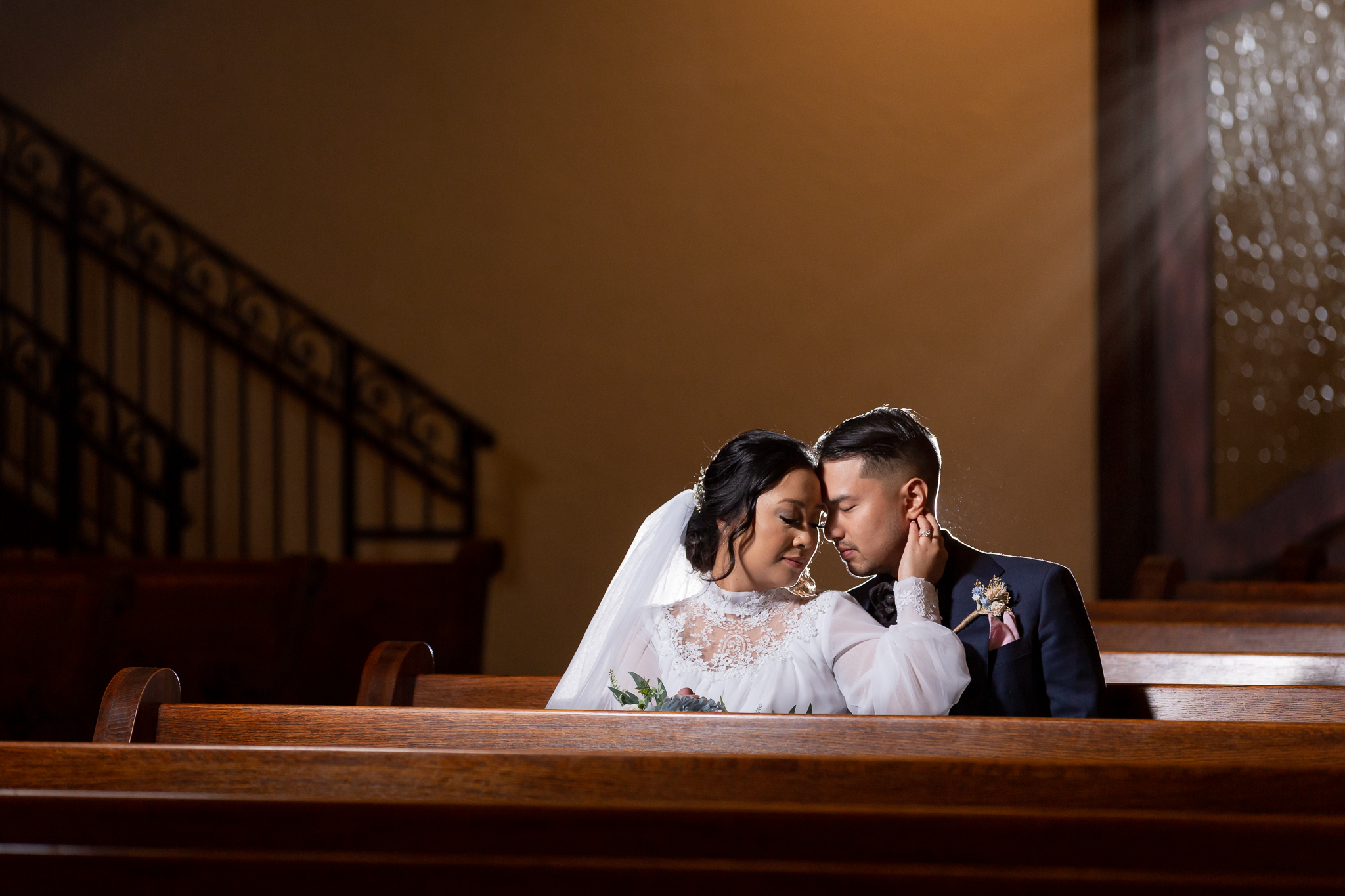 Bride and groom snuggled up in pew in the Chapel at Ana Villa's ceremony chapel in Texas photographed by Dallas wedding photographer