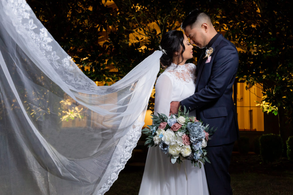 Bride and groom foreheads touching with veil flowing behind them in Dallas Texas at Chapel at Ana Villa