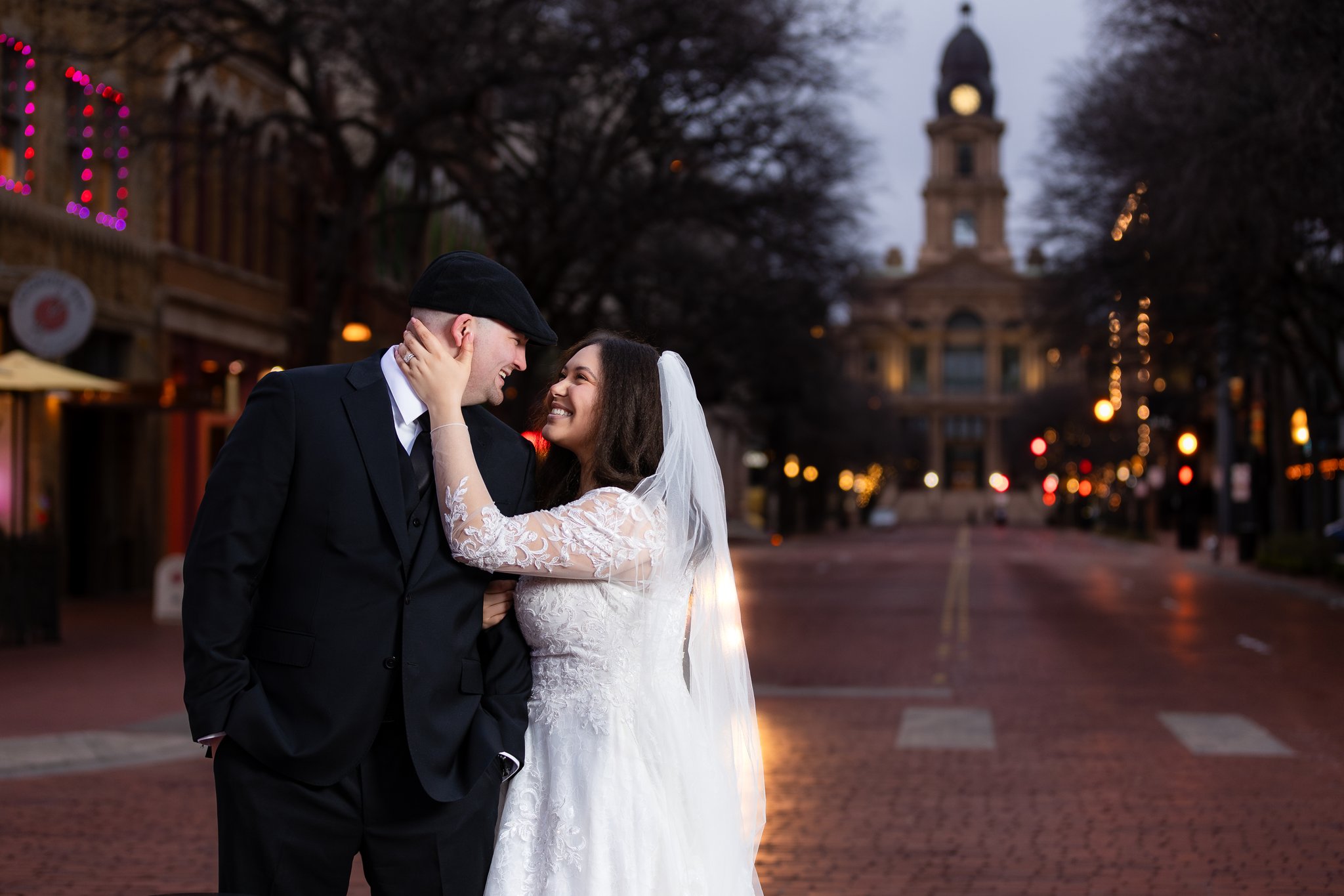 Wedding couple smiling at each other intimately in downtown Fort Worth with Tarrant County Courthouse in background