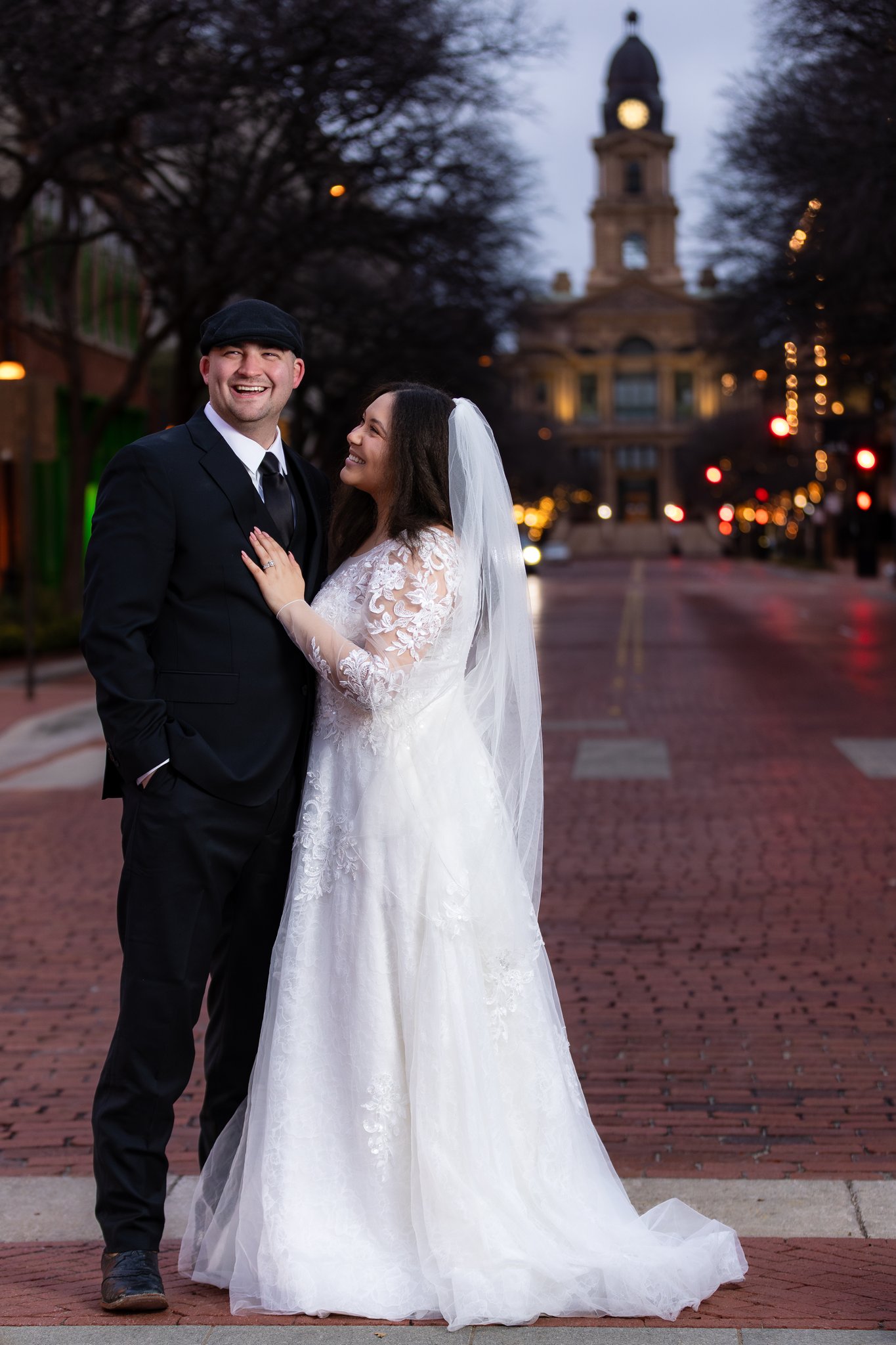 Bride smiling at groom in downtown Fort Worth with Tarrant County Courthouse behind them