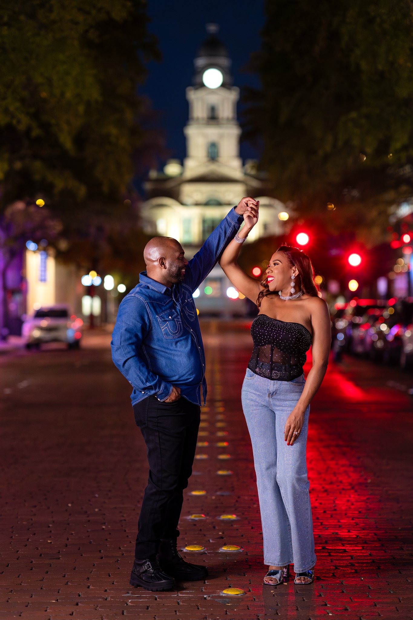 Engaged couple twirling and dancing in middle of street in downtown Fort Worth