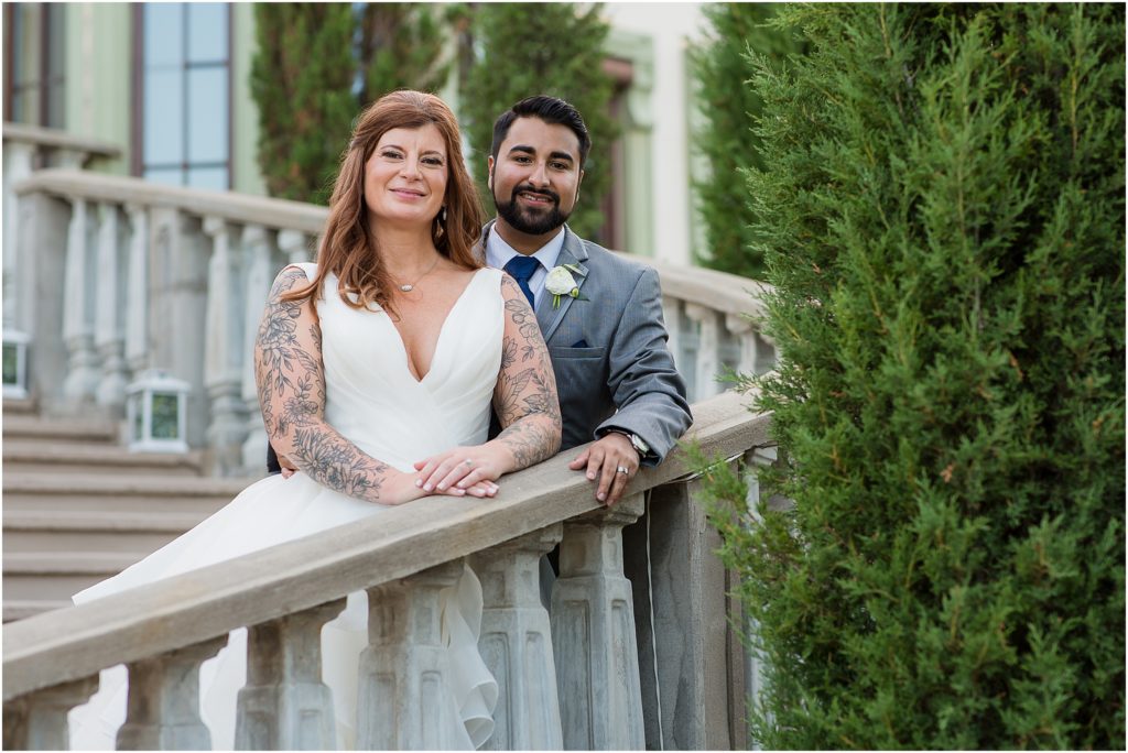 groom standing behind his bride on an outdoor stairwell as they both rest their hands on the railing photographed by Dallas wedding photographers