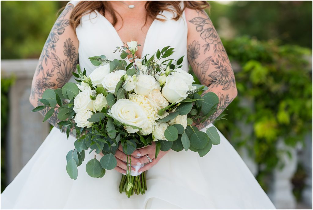 beautiful tattooed bride holding white flower bouquet with soft greenery photographed by Dallas wedding photographers
