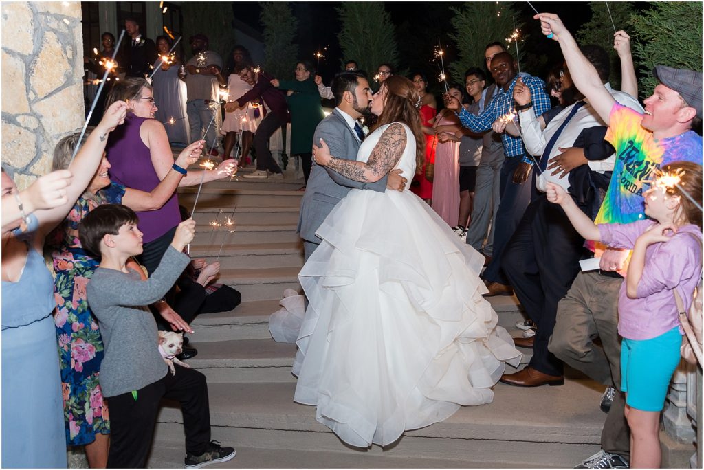 Sparkler Exit on steps of Stoney Ridge Villa wedding venue with bride and groom kissing amongst their wedding guests
