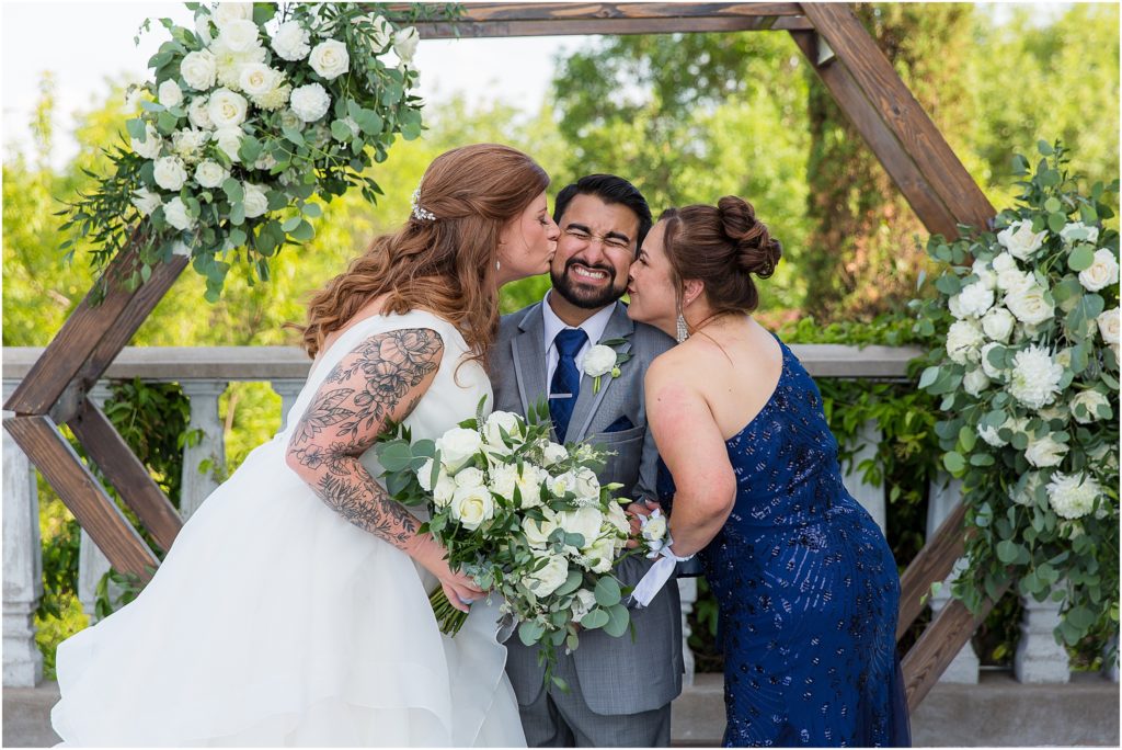 mother and bride sandwich kissing groom on cheeks captured by Dallas wedding photographers