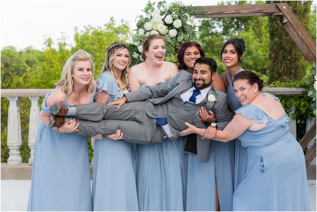 Dallas wedding photographers photographs bridesmaids carrying groom and all laughing