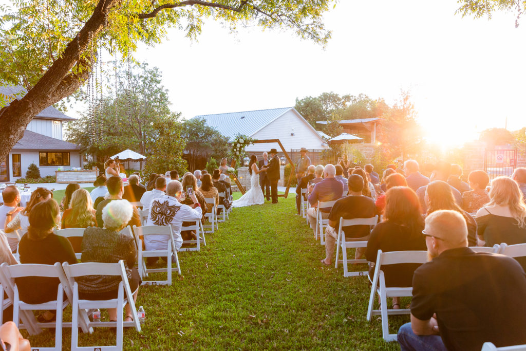 sunset wedding ceremony with bride and groom holding hands and sharing their vows to each other for their outdoor ceremony in Dallas photographed by Dallas wedding photographer
