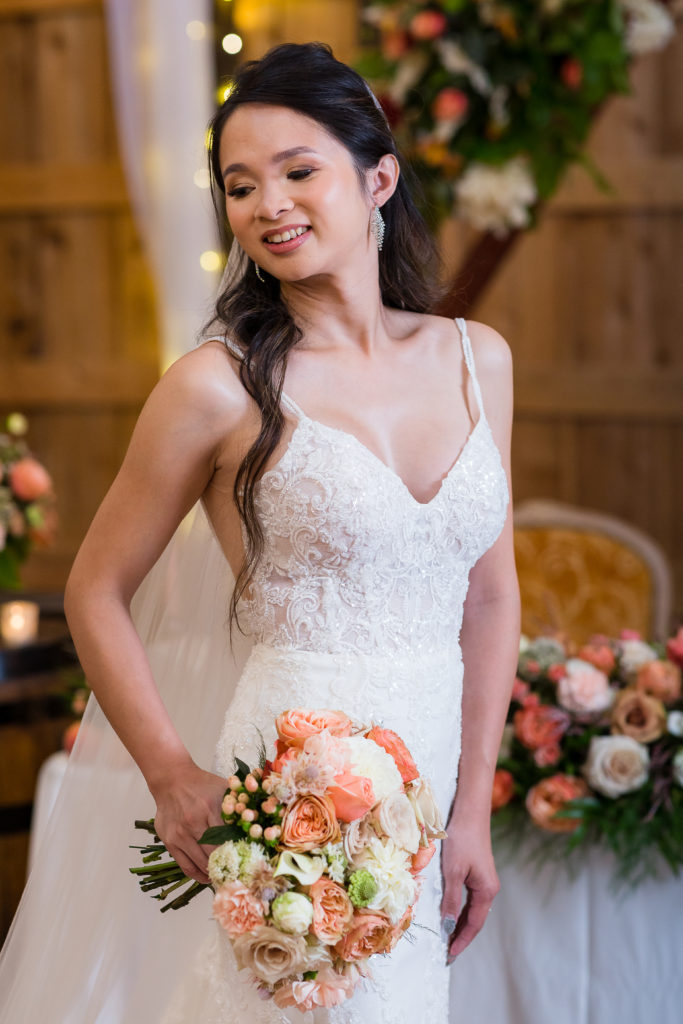 indoor barn wedding with twinkle lights and floral decorating the reception hall with bride in an elegant lace wedding dress
