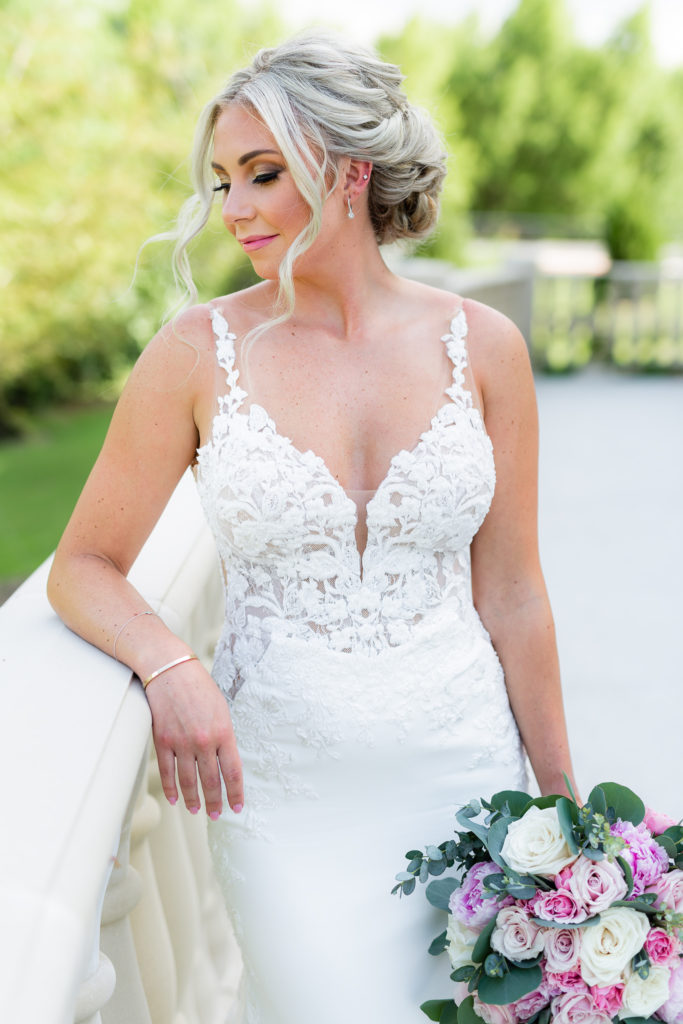 Dallas wedding photographers capture a simple closeup portrait of a blonde bride who looks over an ornamental fence at a luxury wedding venue, the bride's makeup is a prominent gold smoky eye